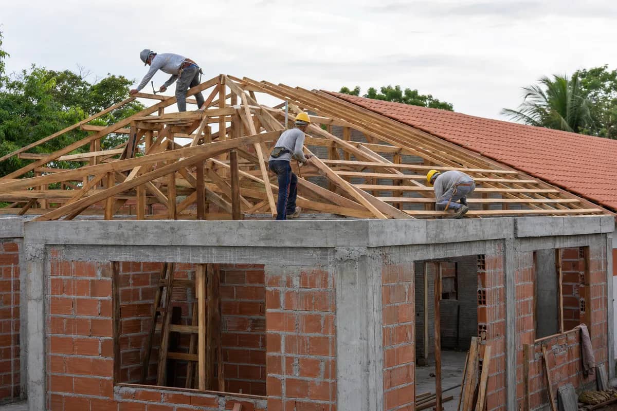 Equipe instalando a estrutura de madeira e as telhas cerâmicas da cobertura escolar