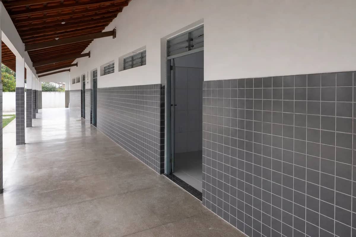 Corredor escolar com paredes renovadas e revestimento cerâmico cinza em Baía da Traição