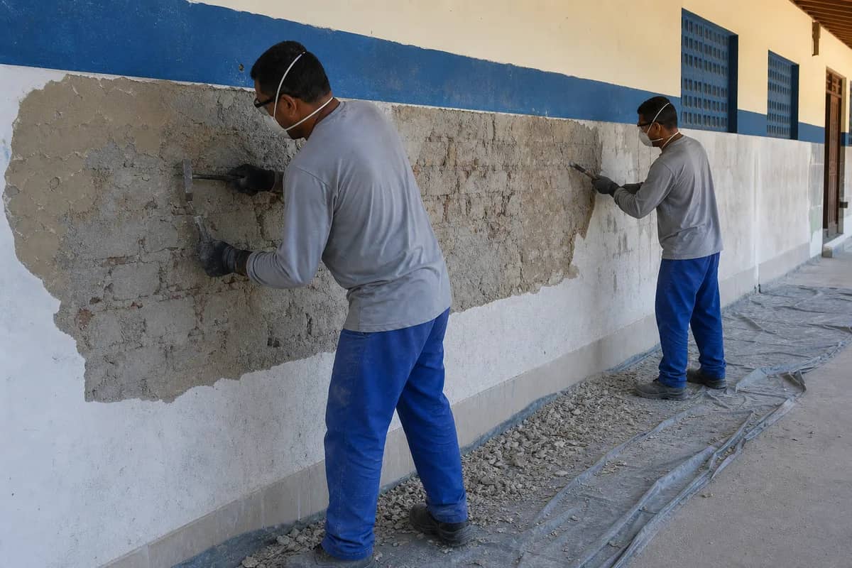 Equipe preparando paredes de uma escola para recomposição do reboco