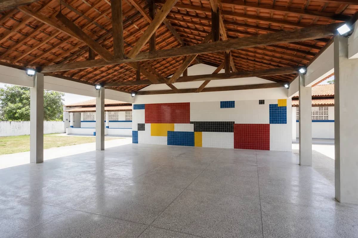Recreio coberto de escola com estrutura de madeira, iluminação e painel cerâmico colorido em Caaporã